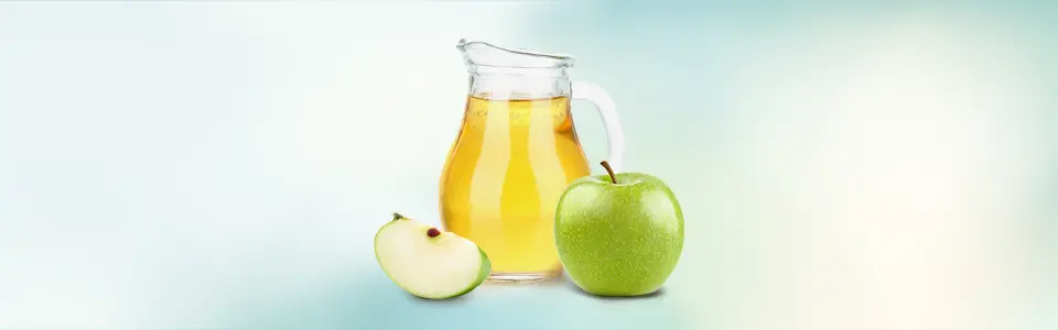 A green apple beside a glass of apple juice